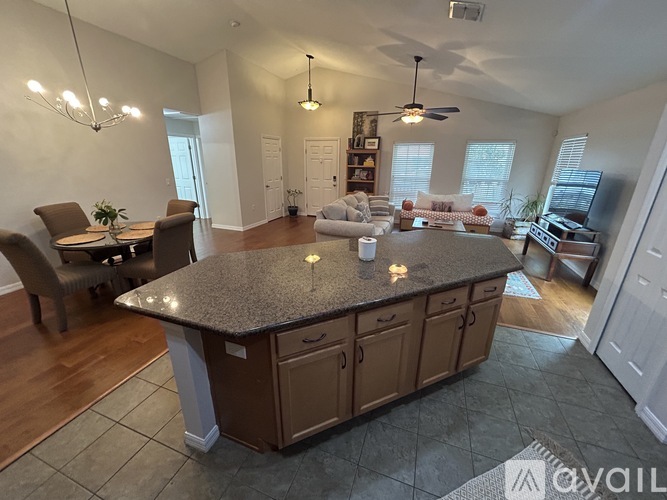 A kitchen island with a countertop and cabinets is in the middle of a room with a dining table and chairs.