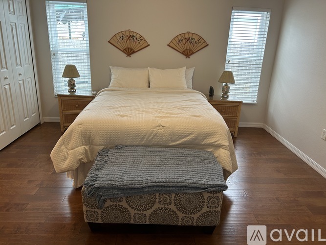 A bedroom with a large bed and a window with blinds.