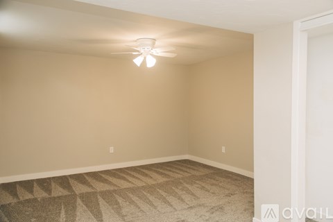A room with a ceiling fan and carpeted floor.