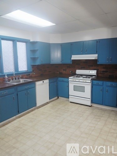 A kitchen with blue cabinets and a white stove top oven.
