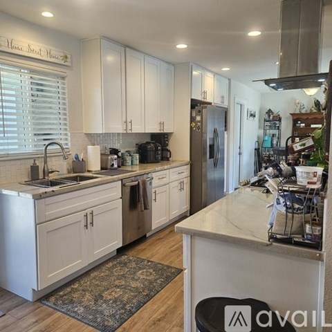 A kitchen with white cabinets and a marble countertop.