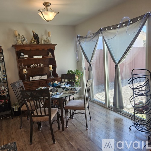 A dining room with a table set for two and a chandelier hanging from the ceiling.