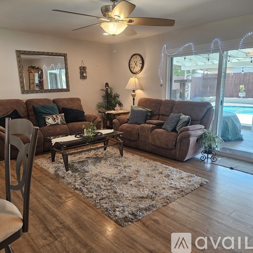 A living room with a brown couch, a coffee table, and a ceiling fan.
