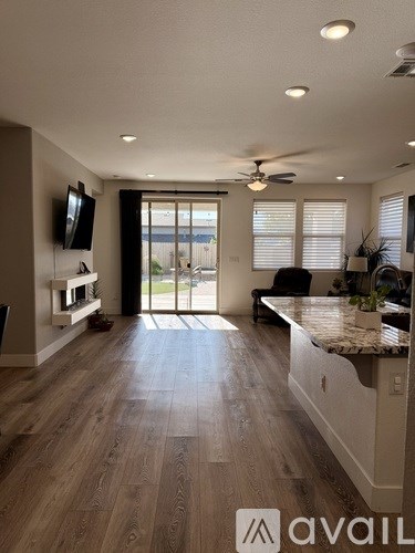 A modern kitchen with a TV mounted on the wall and a sliding glass door leading to a balcony.