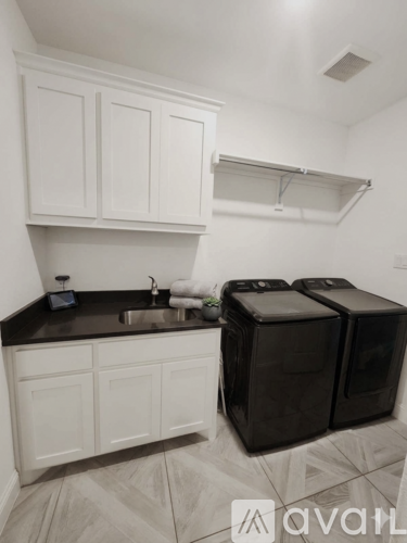 A kitchen with white cabinets and black countertops.
