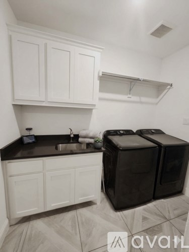 A kitchen with white cabinets and black countertops.
