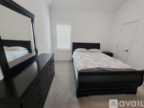 A bedroom with two beds, one with a black headboard and footboard, and a dresser with a mirror.