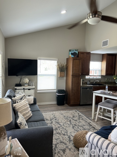 A living room with a grey couch and a television on the wall.