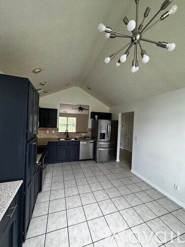 A kitchen with a black refrigerator and a ceiling fan.
