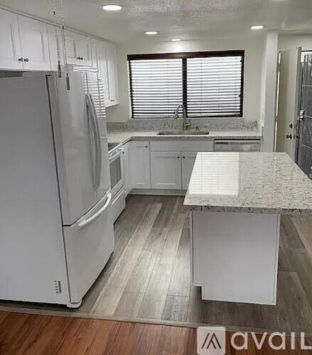 A kitchen with white cabinets and a refrigerator.