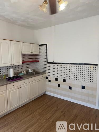 A kitchen with white cabinets and a black and white checkered backsplash.