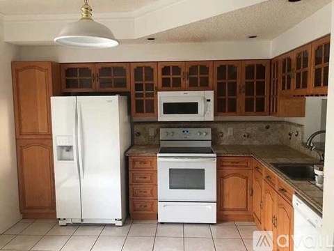 A kitchen with white appliances and wooden cabinets.