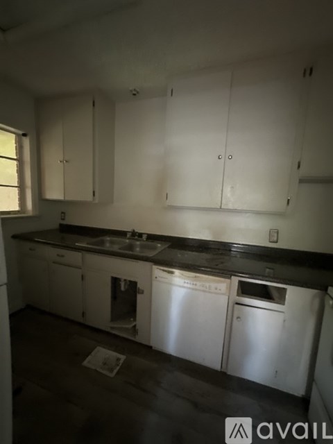 A kitchen with white cabinets and a black countertop.