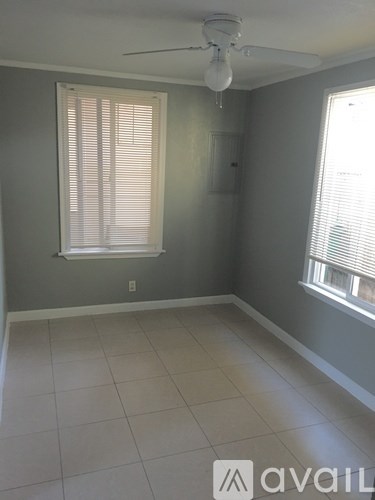 A room with a ceiling fan and two windows.