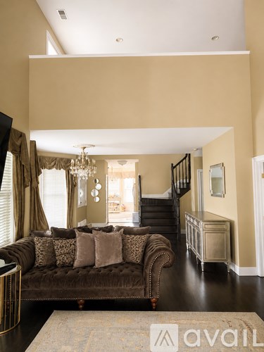 A living room with a brown couch and a chandelier.