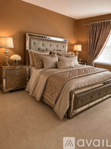 A bedroom with a large bed, a nightstand with a lamp, and a window with curtains.