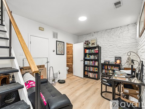 A living room with a black leather couch and a bookshelf filled with books.