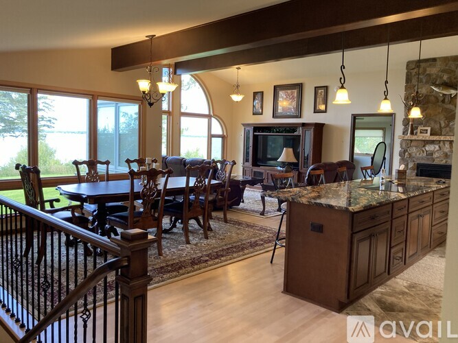 A large, well-lit living room with a dining table and chairs, a fireplace, and a television.