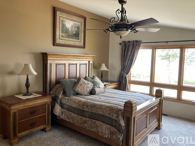 A bedroom with a bed, nightstand, and a painting on the wall.