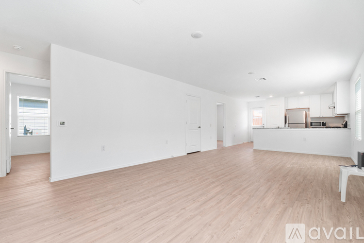 A spacious room with wooden flooring and white walls.