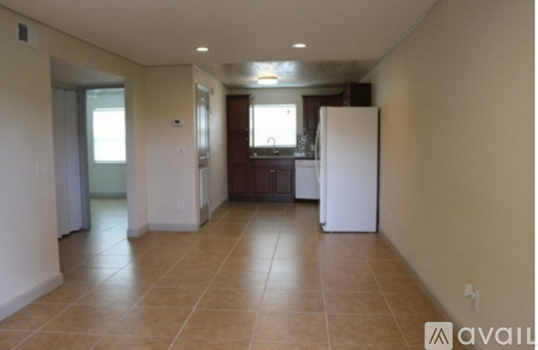 A spacious room with a white refrigerator and brown tile flooring.
