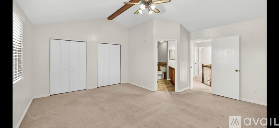 A spacious room with a ceiling fan and three closets.
