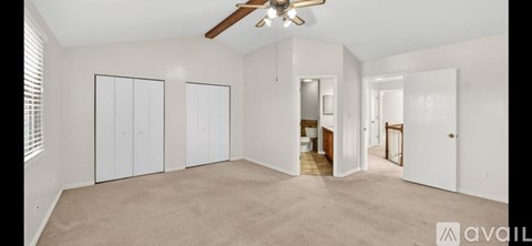 A spacious room with a ceiling fan and three closets.