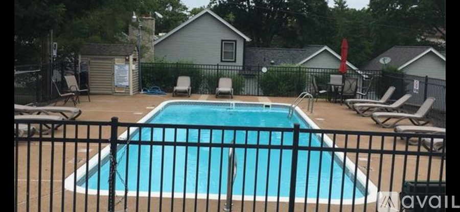 A pool surrounded by a black fence and chairs.