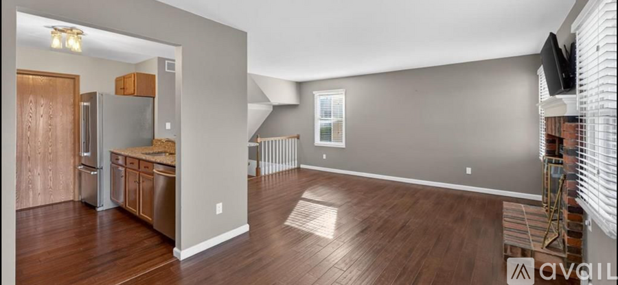 A spacious kitchen with wood flooring and a refrigerator.