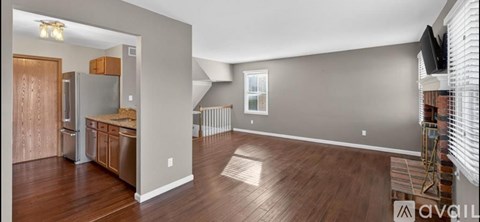 A spacious kitchen with wood flooring and a refrigerator.