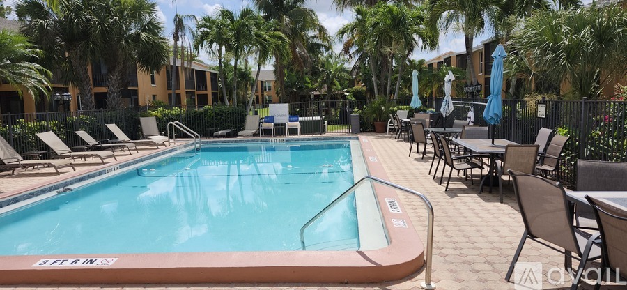 A pool surrounded by chairs and palm trees.