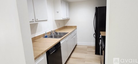 A kitchen with white cabinets and a black refrigerator.