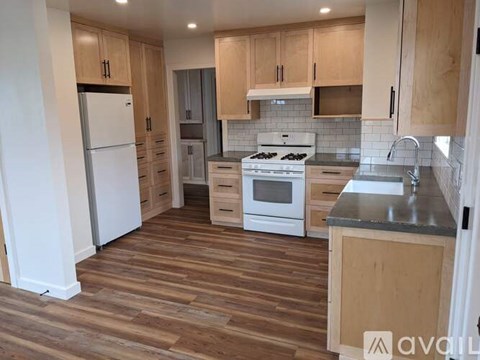 A kitchen with wooden floors and white appliances.