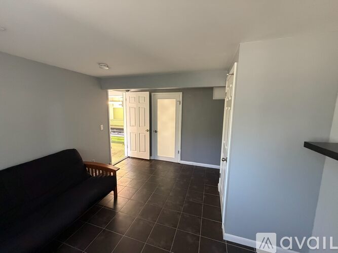 A living room with a black couch and a tiled floor.