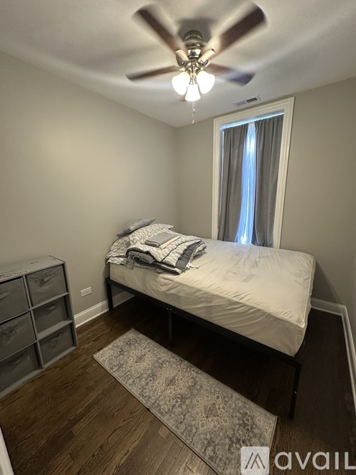 A bedroom with a bed, dresser, and ceiling fan.