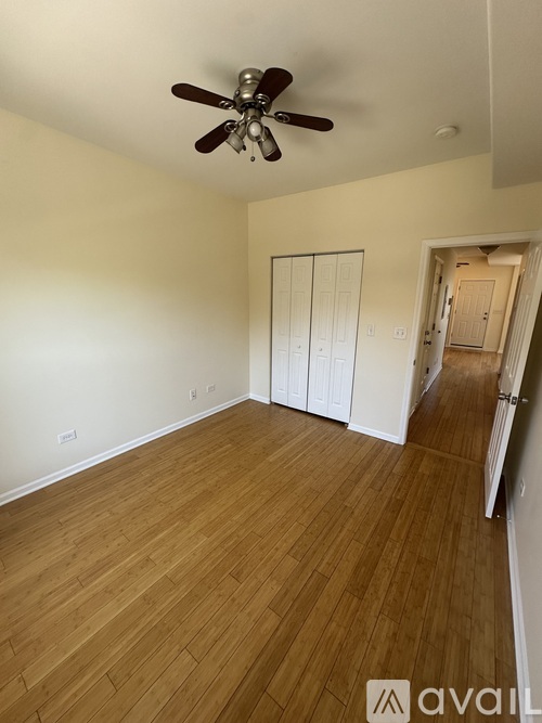 A room with a ceiling fan and wooden flooring.