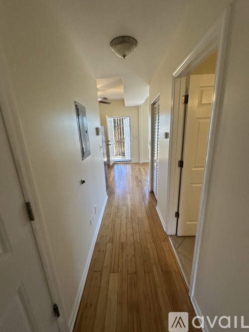A long hallway with a door on the right and a picture on the wall.