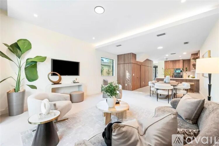 A modern living room with a grey sofa, a white armchair, a wooden coffee table, and a television on a wooden stand.