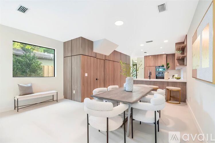 A modern dining room with a wooden table and white chairs.