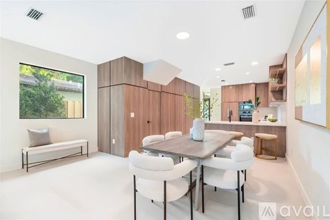 A modern dining room with a wooden table and white chairs.