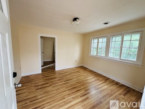 A room with wooden flooring and a window with a view of trees.