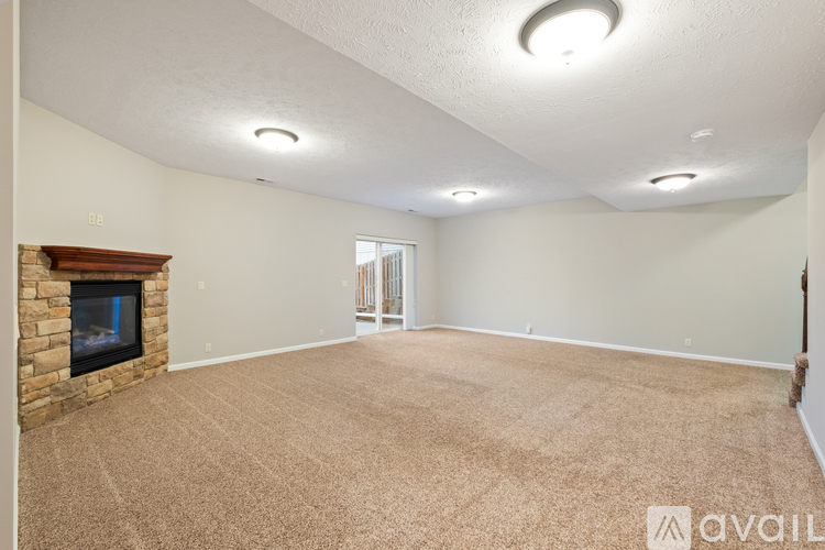 A spacious room with a fireplace and carpeted floor.