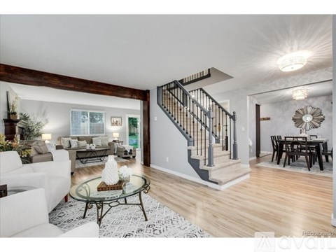 A living room with a glass coffee table and a staircase.