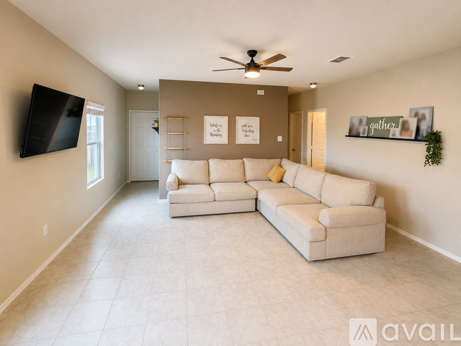A living room with a white couch and a flat screen TV mounted on the wall.