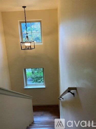 A light fixture hangs over a staircase with a window in the background.