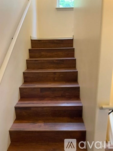A set of wooden stairs with a white wall on the side.