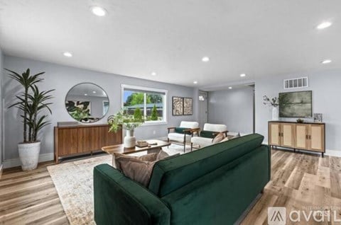A living room with a green couch and a wooden cabinet.