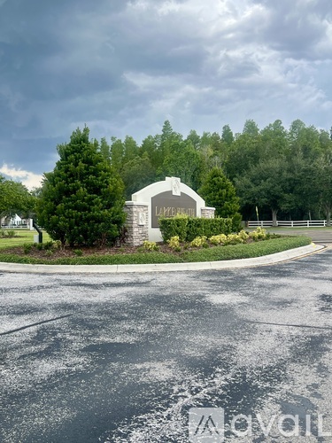A white building with a curved roof is surrounded by greenery and trees.