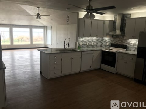 A kitchen with white cabinets and a wooden floor.