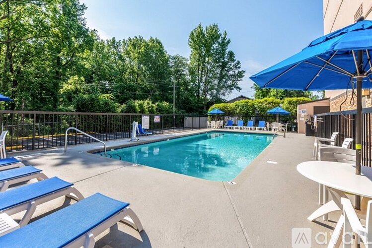 A pool surrounded by trees and chairs.